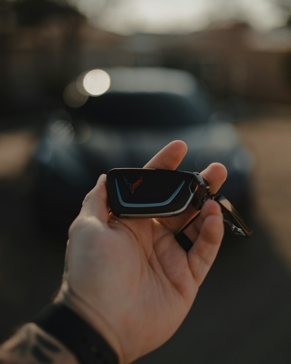 black and red smart watch car keys and car in the background